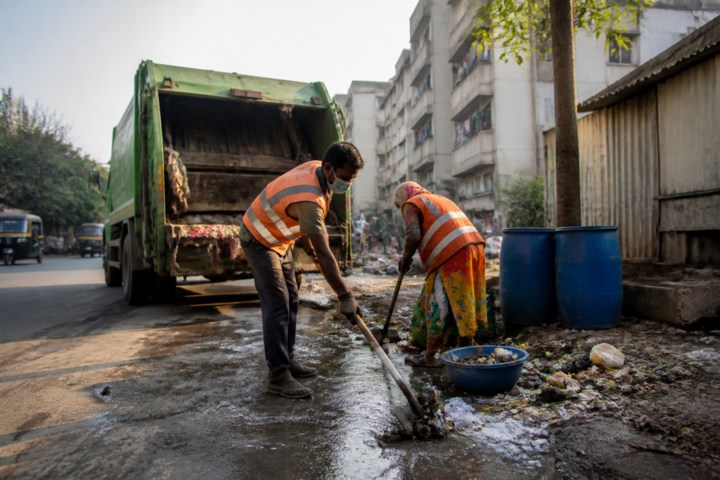 Waste collection vehicle and municipal sanitation workers on a street in Vasai-Virar