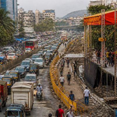 Traffic moving past a Dahi Handi celebration stage on a crowded road in Ambernath