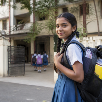 Student carrying a schoolbag outside a Maharashtra school, illustrating the state's 10% schoolbag weight limit