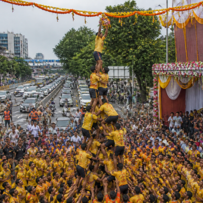 Govinda teams form a human pyramid during a Dahi Handi event on a busy road in Thane