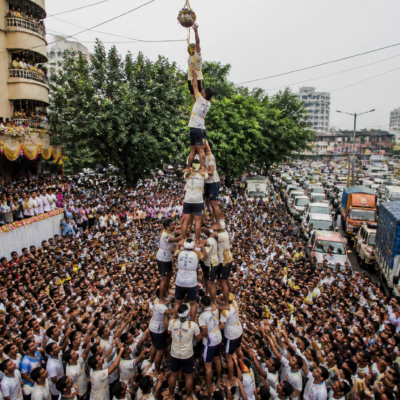 Govinda participants forming a human pyramid during a Dahi Handi celebration on a crowded Vasai-Virar road