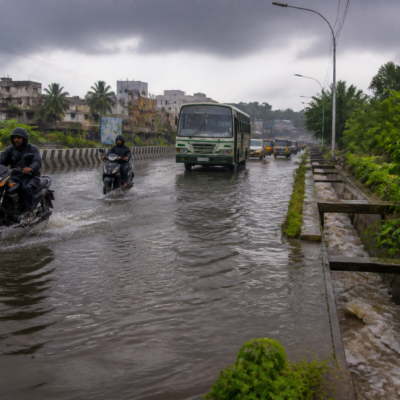 Tamil Nadu rain alert over a flooded urban road with commuters and dark monsoon clouds