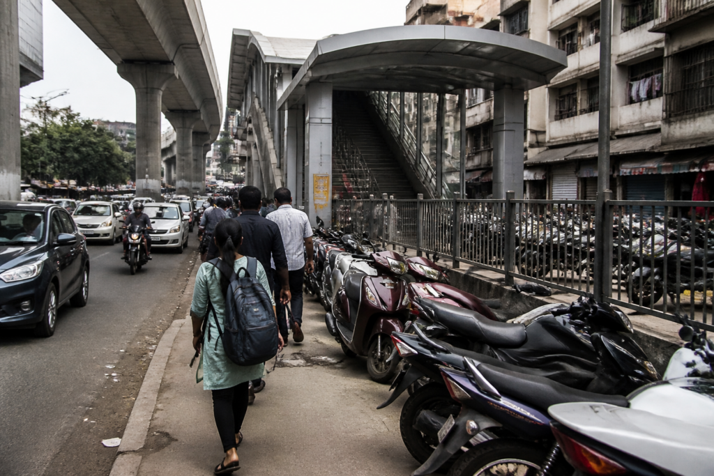 Pune Metro footpaths blocked by station access structures and parked two-wheelers near a busy road.
