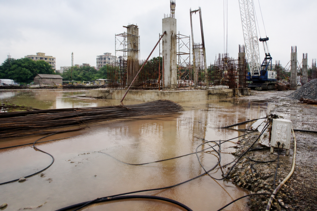 Ahmedabad construction site with standing water and temporary electrical wiring