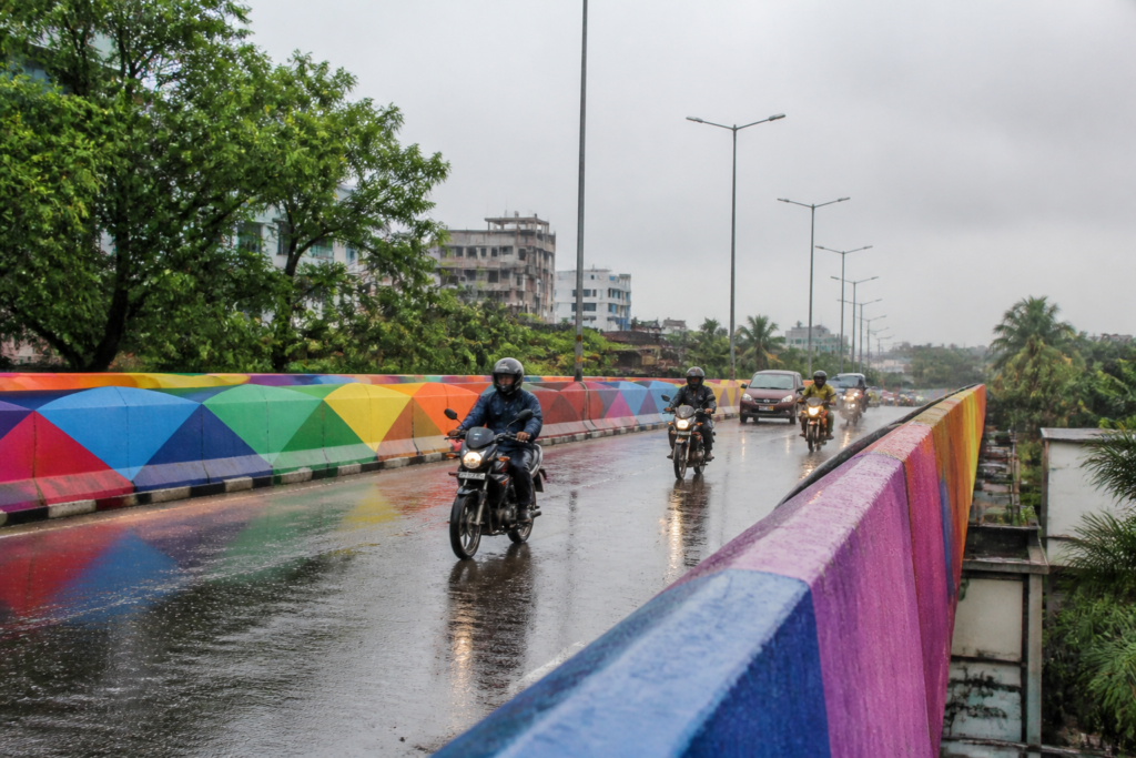 Kolkata rainbow flyover with wet road surface and passing motorcycles