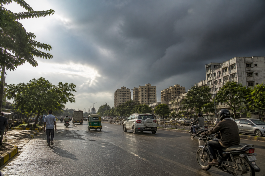 Gujarat rain forecast over a hot Ahmedabad street with dark monsoon clouds