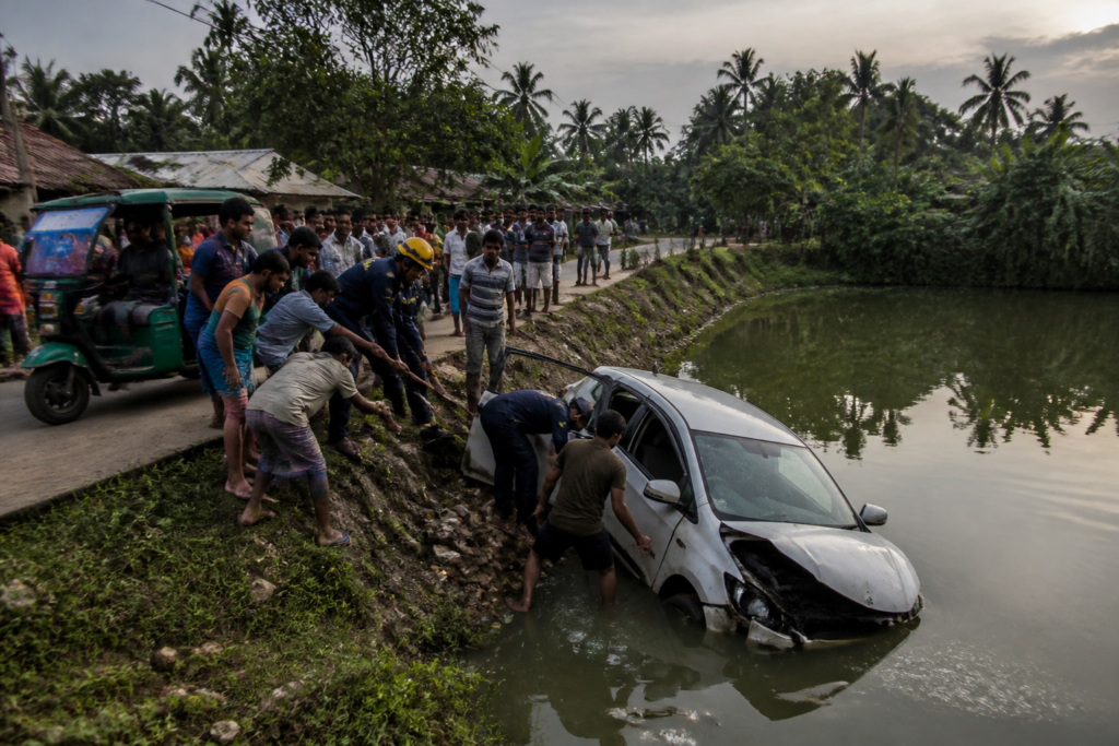 Sandeshkhali accident scene near a pond with a damaged car and rescue activity