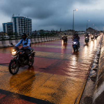 Rain-wet Chingrighata flyover with motorcycles on a coloured road surface in Kolkata