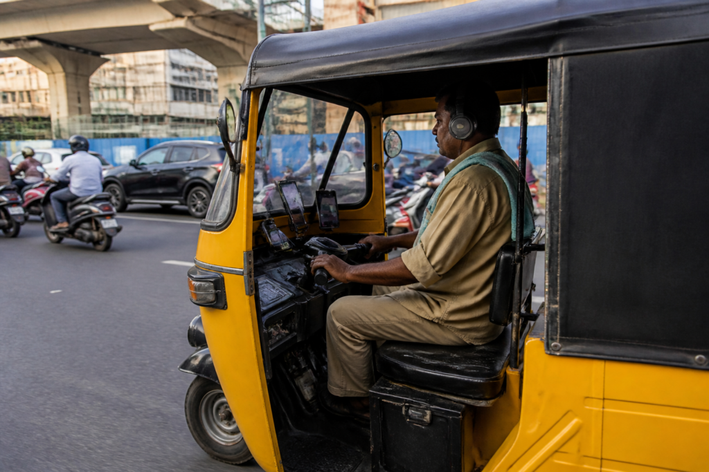 Hyderabad autorickshaw driver using two phones and headphones while driving