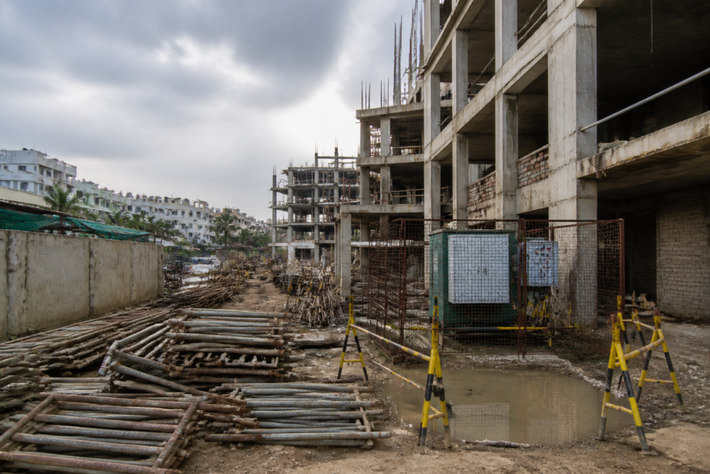 Ahmedabad construction site with safety barriers and exposed electrical wiring near pooled water