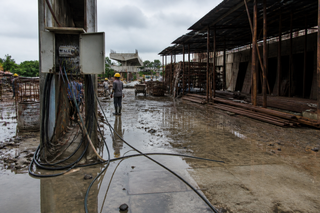 Ahmedabad construction site with exposed electrical wiring and workers near building materials