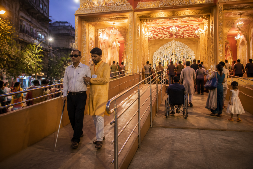 Kolkata Durga Puja pandal with an accessible ramp and visitors using an inclusive entrance