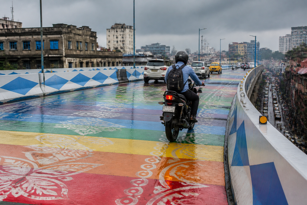 Kolkata rainbow flyover with painted road surface and a motorbike during wet conditions
