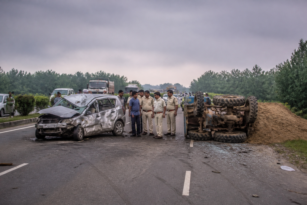 Kanksa crash scene on NH 19 with a damaged car and overturned sand-laden tractor