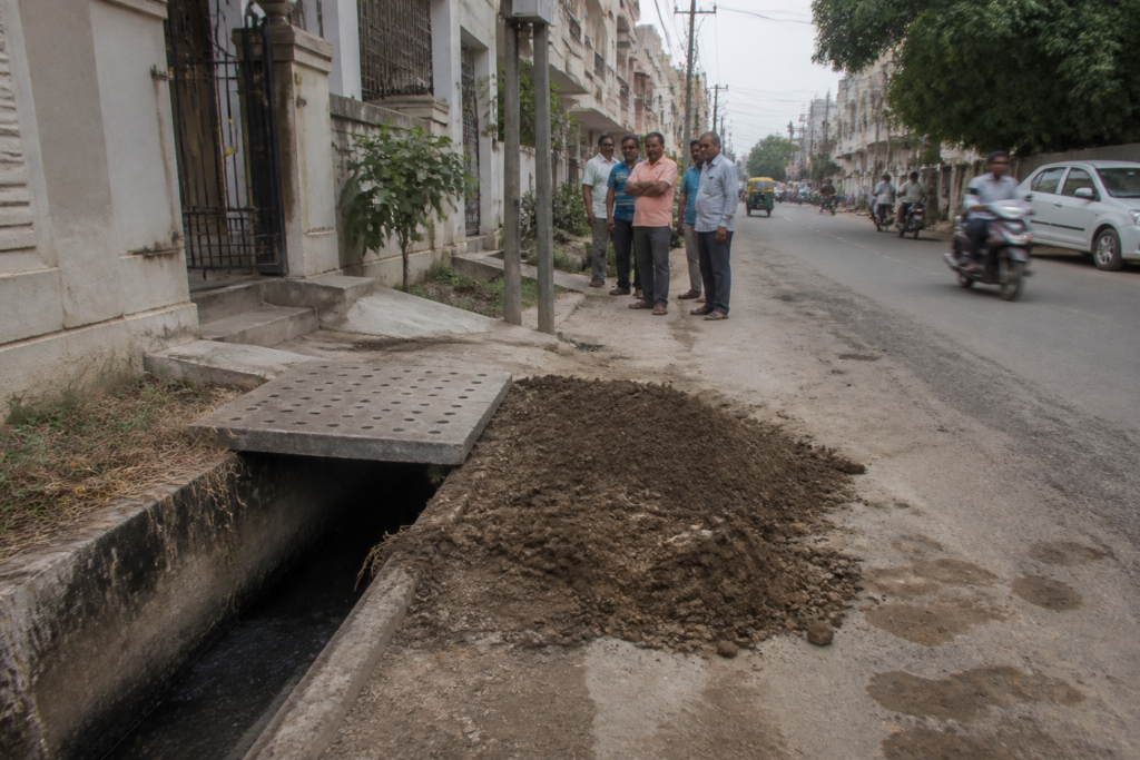 Ahmedabad sewer death site with a covered roadside drain and newly installed warning board