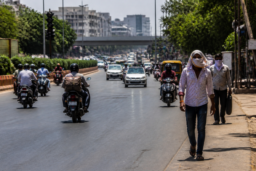 Ahmedabad heatwave conditions with residents navigating a hot city street under harsh October sunlight.