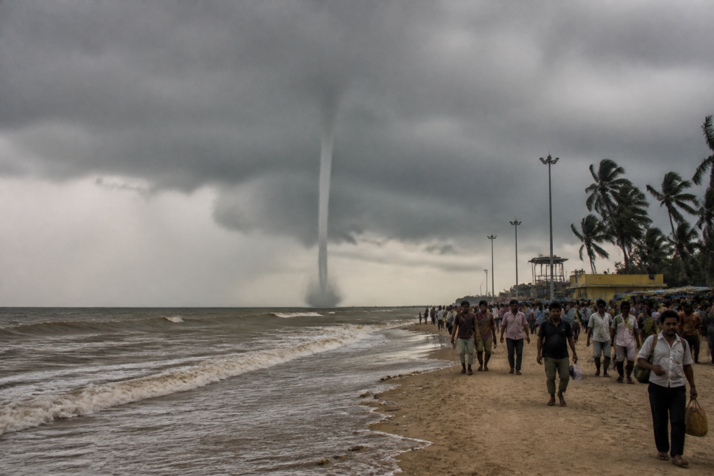 Waterspout near Gangasagar rising from the sea beside a crowded bathing ghat