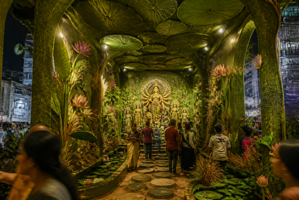 Kolkata Durga Puja pandal depicting an urban pond with aquatic plants and visitors