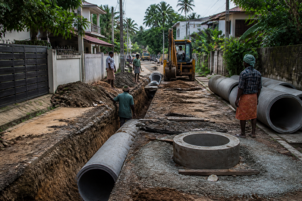 Thiruvananthapuram sewer upgrade work on an urban road with utility crews and underground infrastructure.