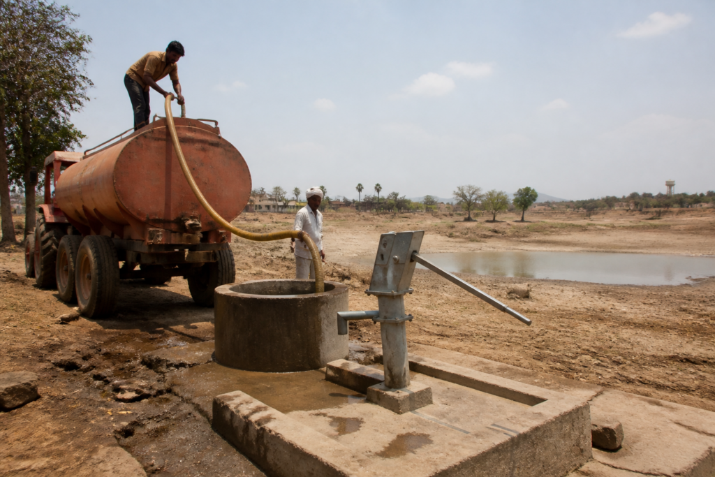 Maharashtra drought mitigation planning with a village water supply tanker near a dry reservoir