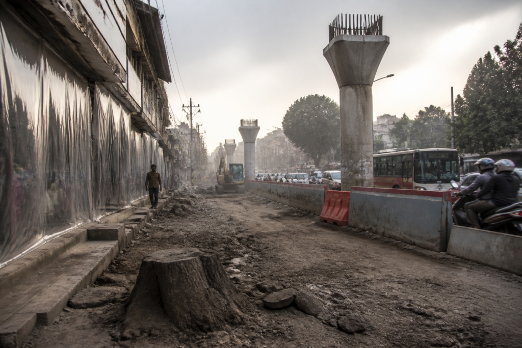 Bhopal Metro construction dust clouds a BHEL road beside shops and unfinished surfaces