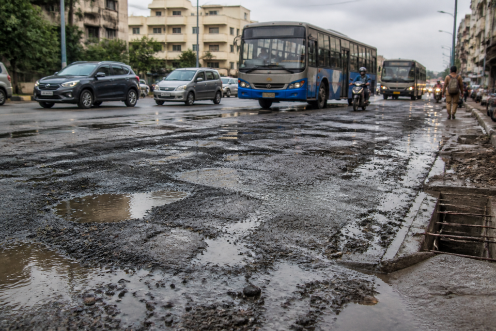 Damaged Chennai bus route road showing uneven asphalt and traffic before the monsoon