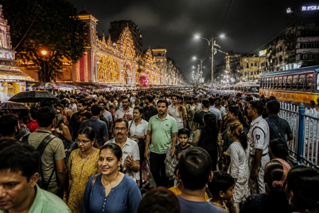 Kolkata Durga Puja crowd walking through a congested pandal route at night