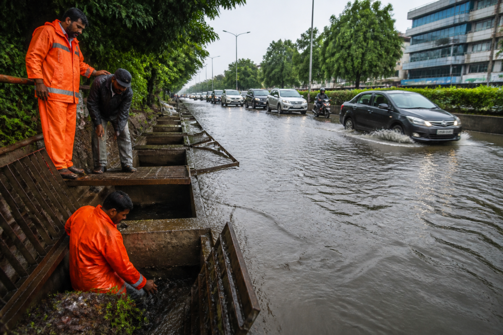 Chandigarh stormwater drains beside a waterlogged road during heavy monsoon rain