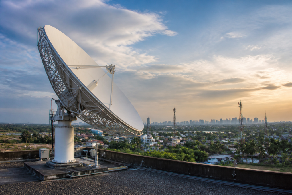 Satcom competition in India represented by a satellite communications antenna above an urban landscape