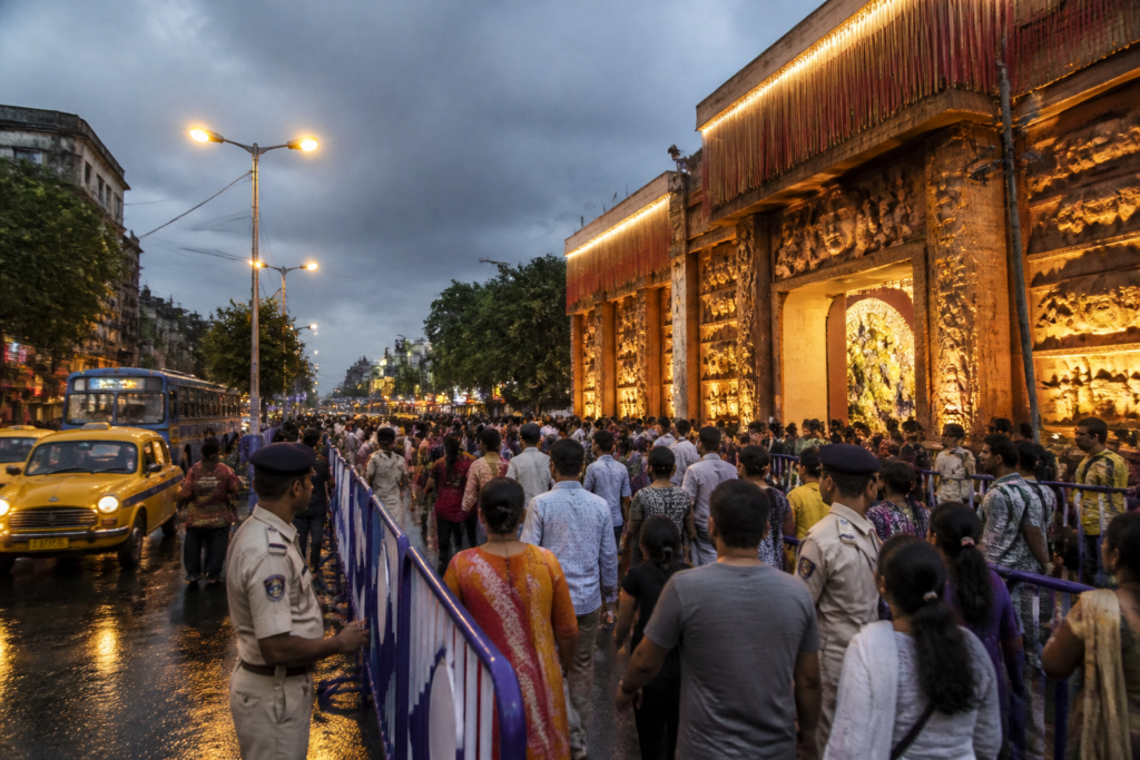 Kolkata Durga Puja 2026 crowds near a decorated pandal with police and public transport in the background