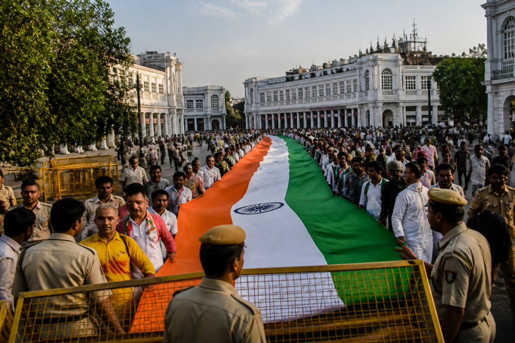 Delhi Tiranga Yatra participants carrying a large Indian national flag during a city procession