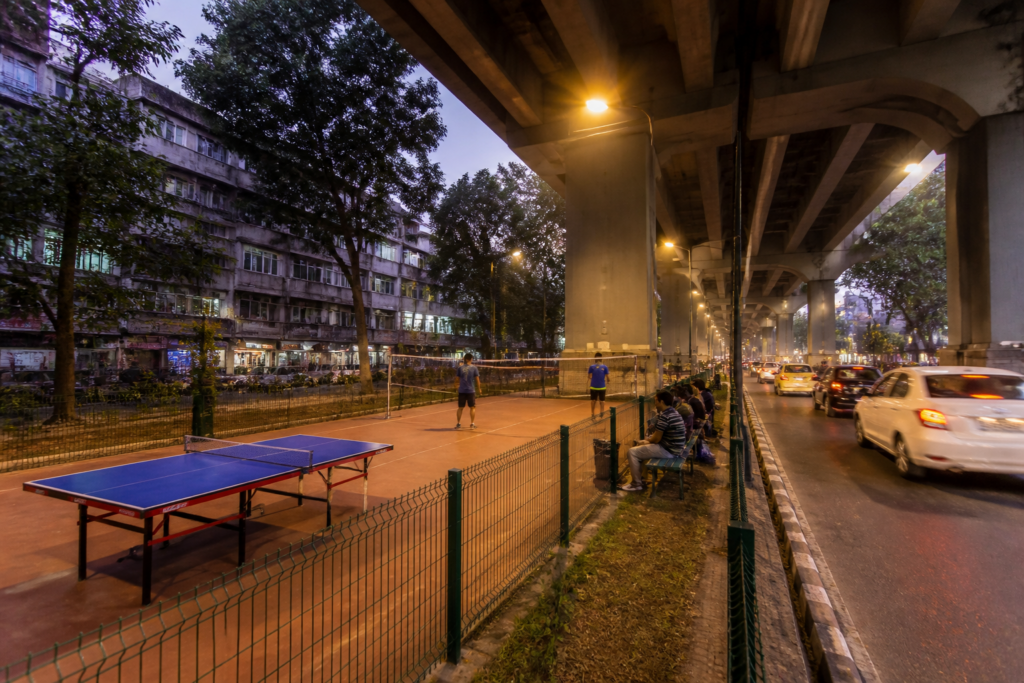 Kolkata sports zones planned beneath a flyover with fenced recreational space and city traffic