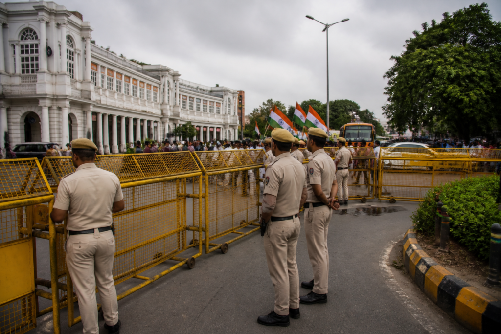 Delhi protest security near Connaught Place with police barricades and flag-waving supporters
