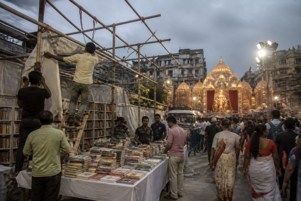 Kolkata puja book stalls being set up beside a crowded pandal area