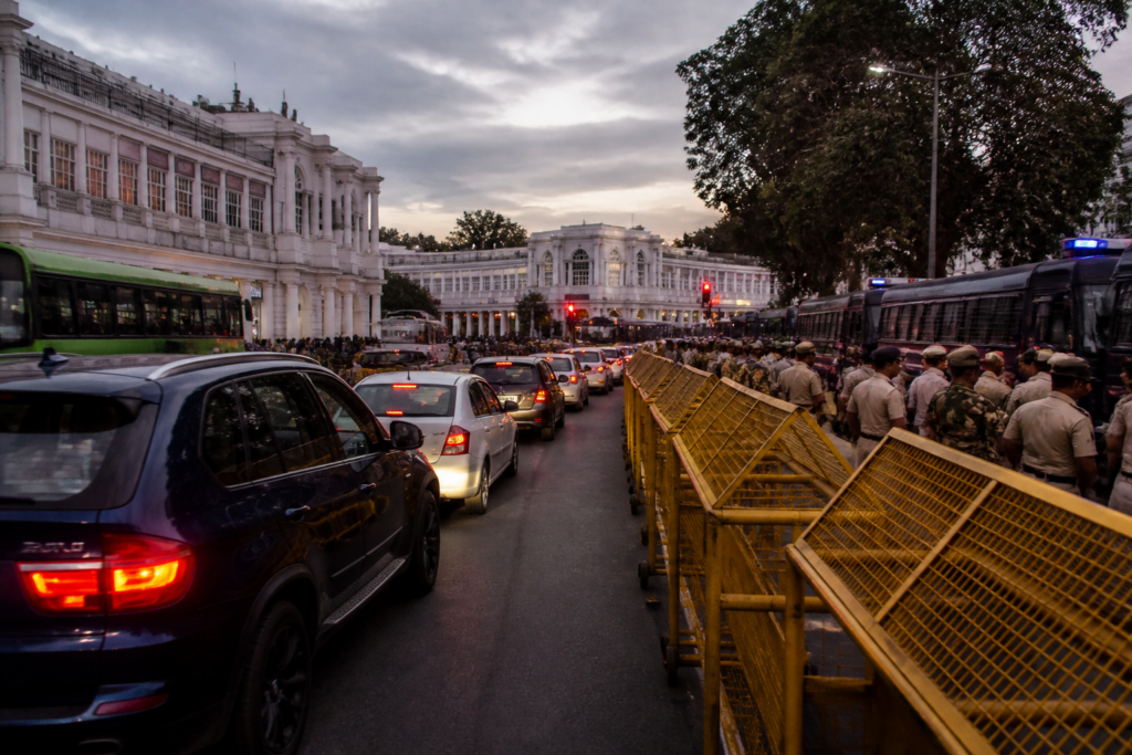 Central Delhi traffic moving past security barricades near Connaught Place during a protest