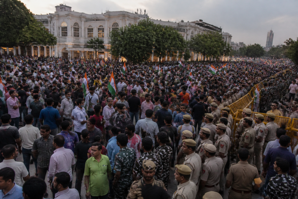 Connaught Place protest with flag-carrying demonstrators and security personnel in Delhi