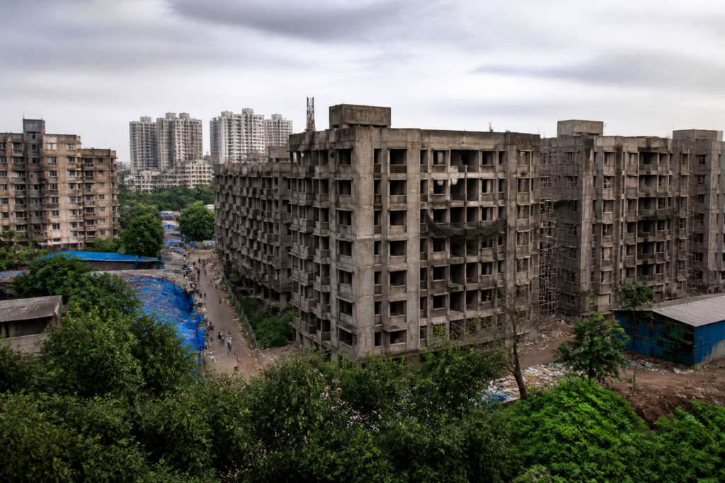 Mumbai slum rehabilitation buildings in Aarey Colony with unfinished construction and dense urban surroundings