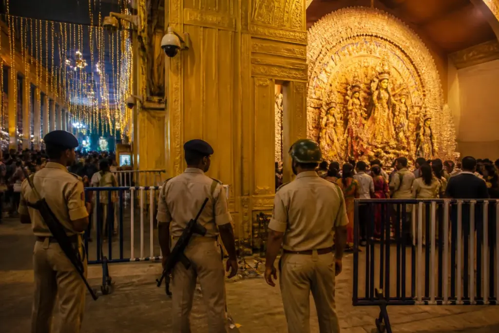 Kolkata Durga Puja security personnel guarding a decorated idol at a festival mandap
