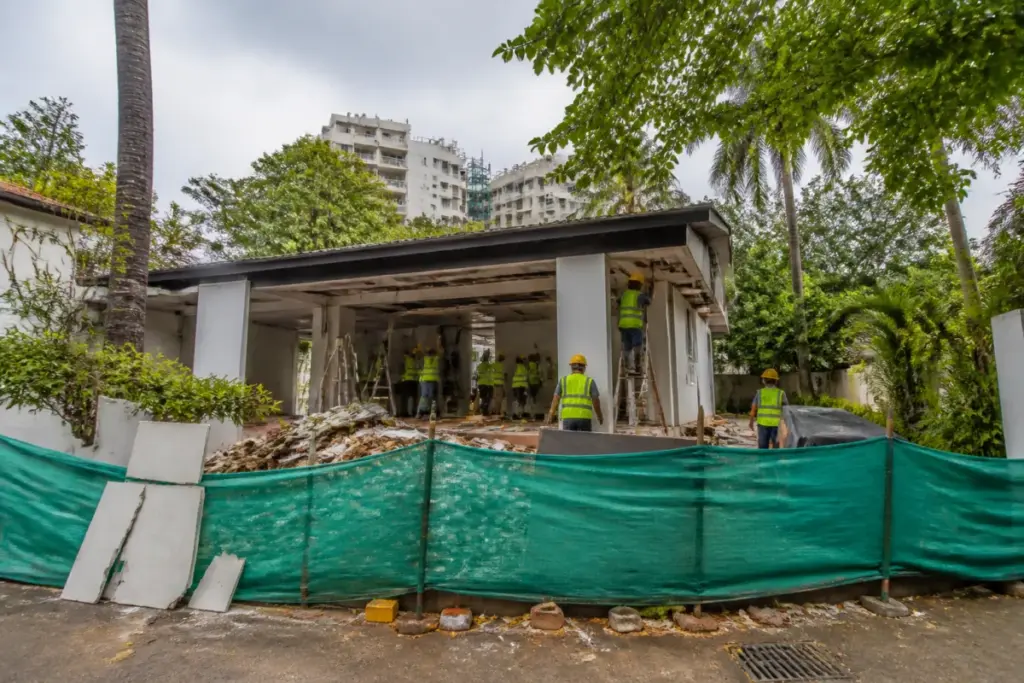 BMC Juhu property demolition at a bungalow with temporary barriers and workers removing unauthorised partitions