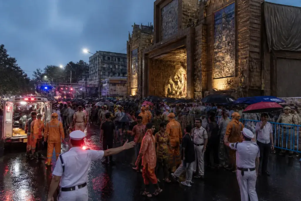 Kolkata pandal accident scene with crowds and emergency responders outside a Durga Puja venue