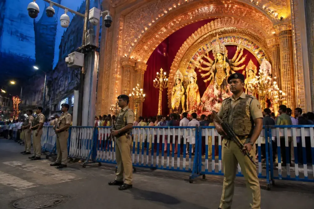 Armed police personnel guarding a Kolkata Durga Puja pandal under CCTV surveillance
