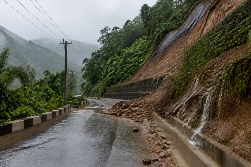 Mizoram landslide mitigation work near a rain-soaked mountain road and vulnerable hillside