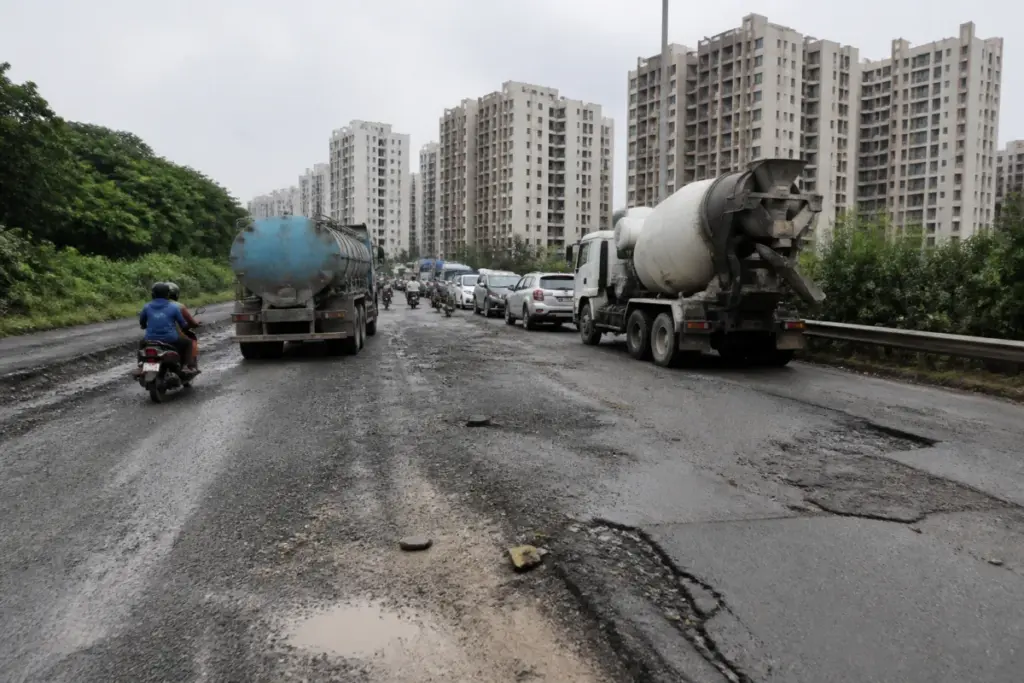 Damaged Pune Undri Road near The Corinthians Club with traffic and cracked road surface