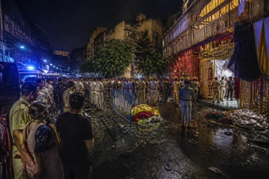Kolkata puja stampede site with a crowded Durga Puja pandal entrance and emergency response