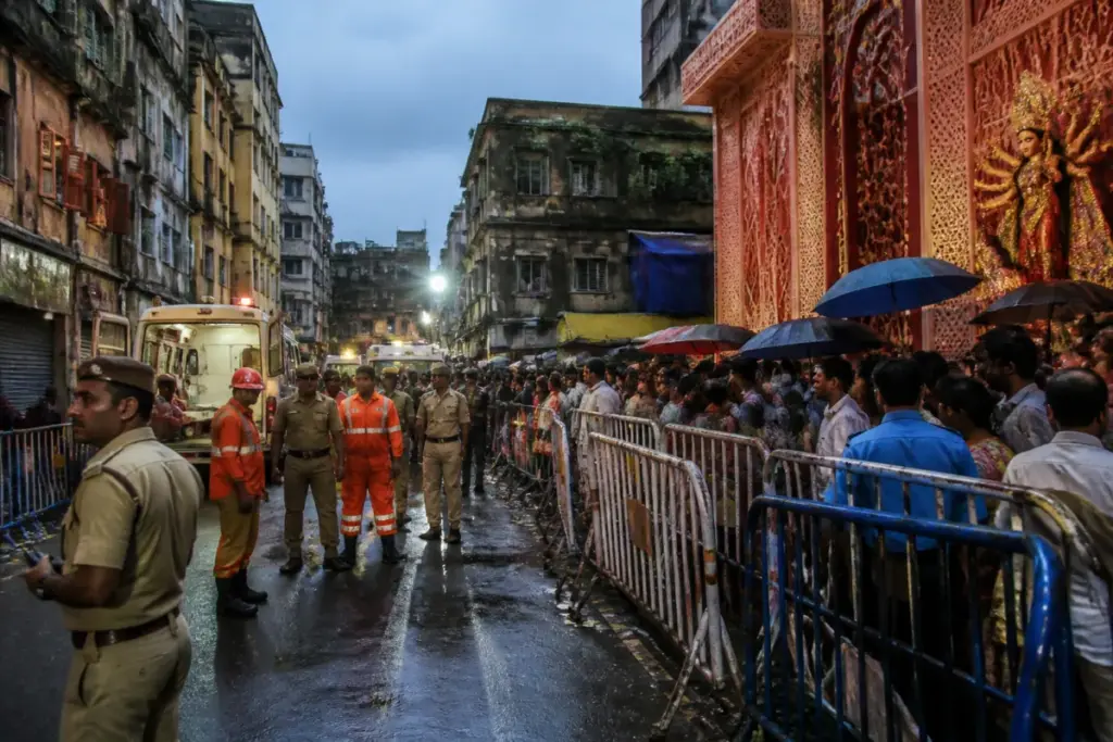 Kolkata pandal stampede site with police barricades and emergency responders near a Durga Puja venue