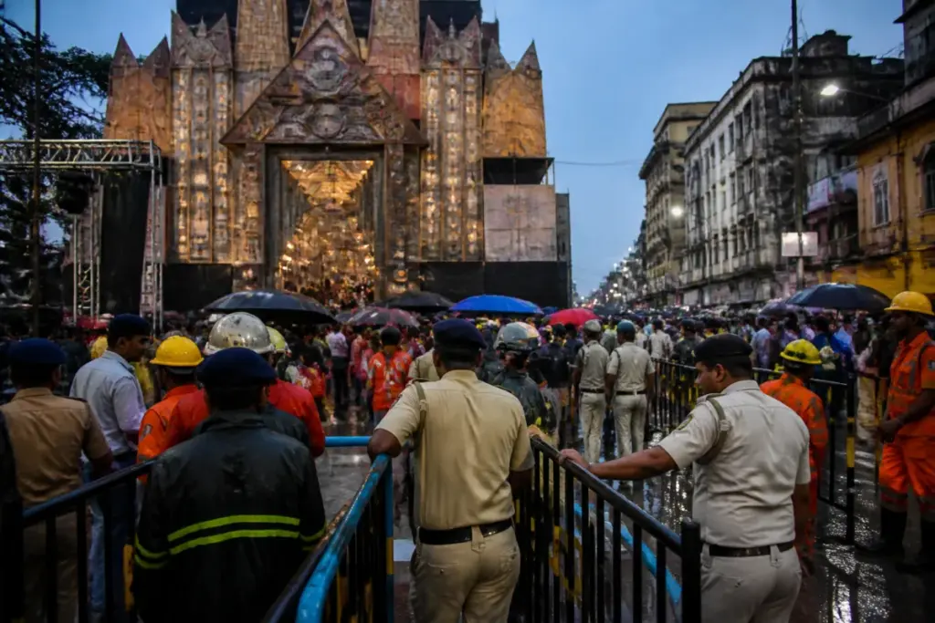 Kolkata pandal stampede site with crowds and emergency responders near a Durga Puja venue