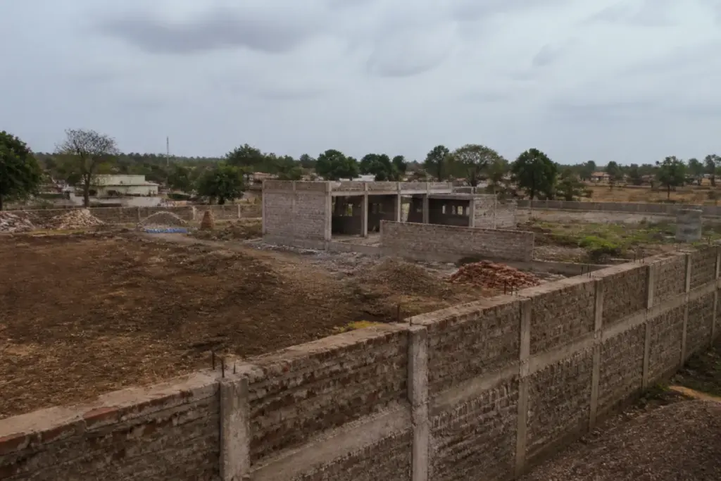 Rewa cowshed fraud case site showing an incomplete boundary wall and unfinished rural structure
