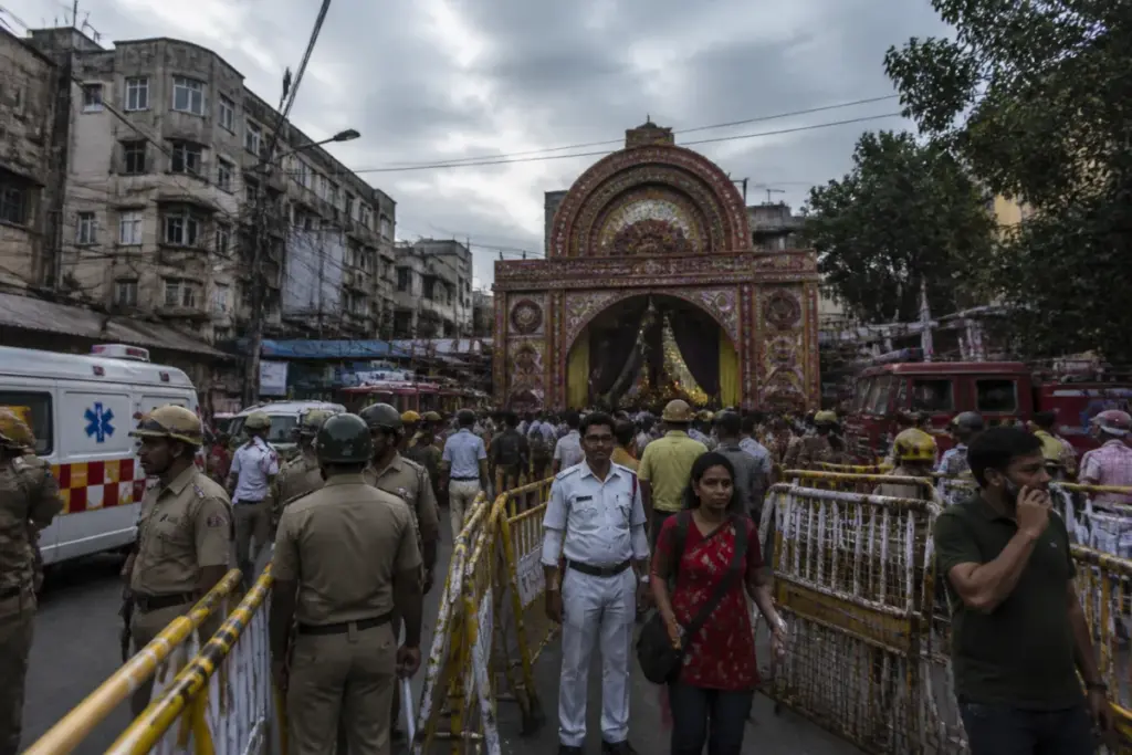 Kolkata Durga Puja stampede site with police barricades and emergency responders near a crowded pandal