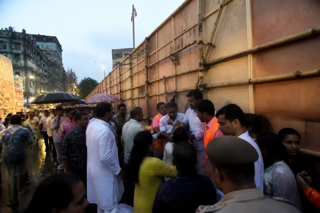 Crowded Kolkata puja pandal exit with visitors gathered near a temporary plywood passage