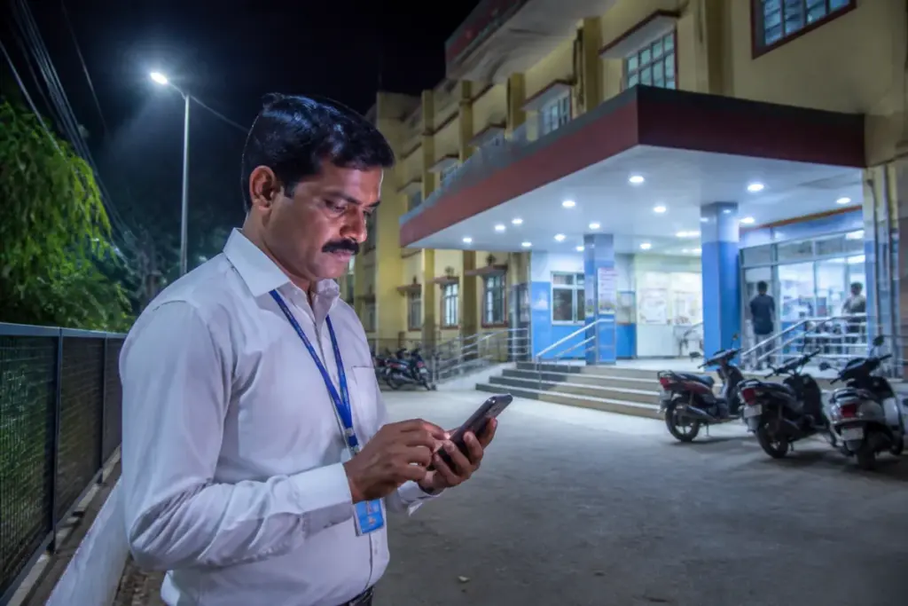 Karnataka Kartavya app attendance system shown on a smartphone near a government health centre